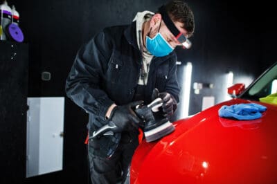 car-detailing-concept-man-face-mask-with-orbital-polisher-repair-shop-polishing-orange-suv-car.jpg